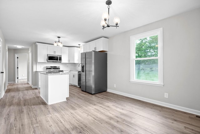 kitchen featuring white cabinets, hanging light fixtures, light wood-type flooring, and appliances with stainless steel finishes