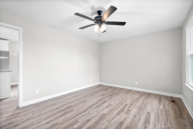 empty room with ceiling fan and light hardwood / wood-style flooring