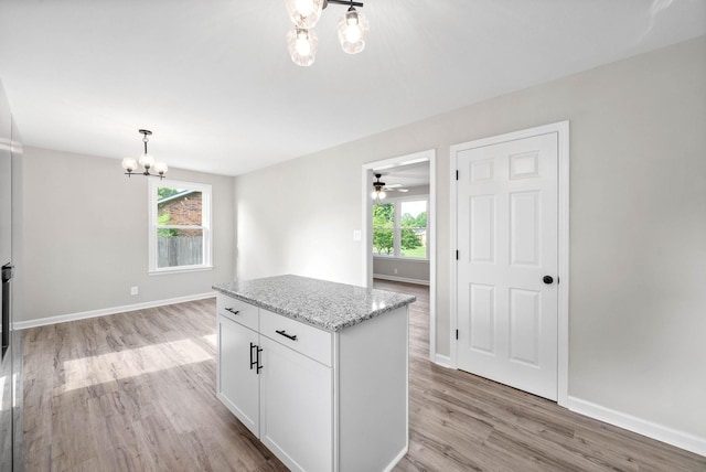 kitchen with light stone counters, light hardwood / wood-style flooring, white cabinets, and pendant lighting