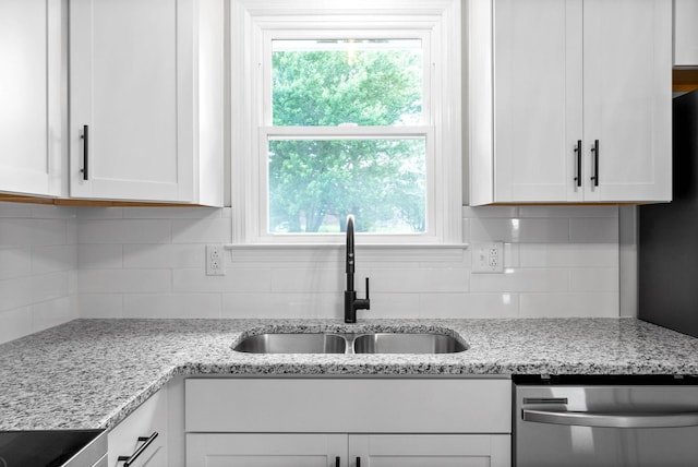 kitchen featuring light stone countertops, white cabinetry, stainless steel dishwasher, and sink