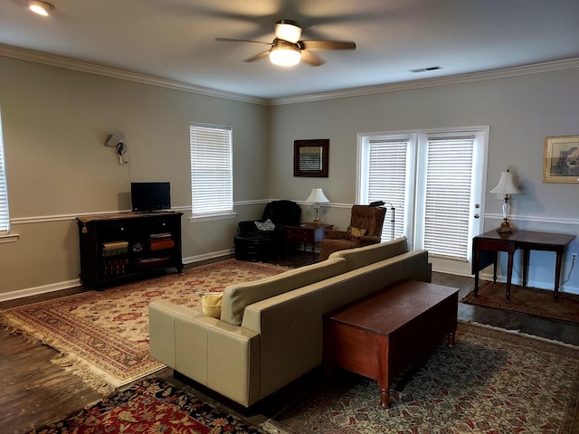 living room with ceiling fan, plenty of natural light, dark wood-type flooring, and ornamental molding