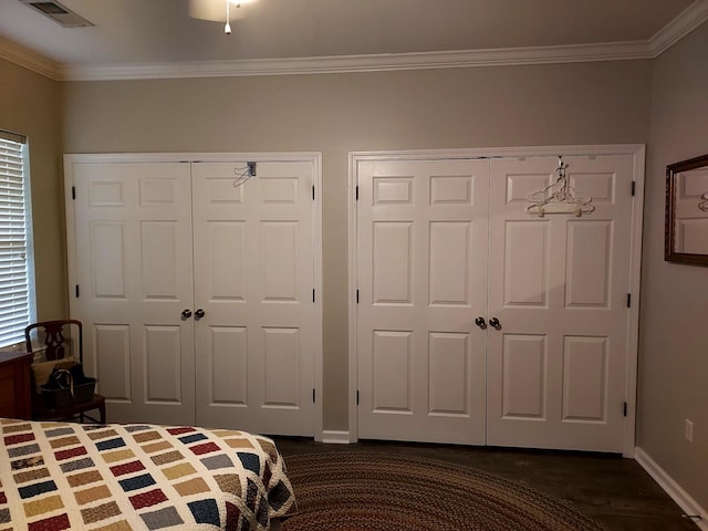 unfurnished bedroom with multiple closets, crown molding, and dark wood-type flooring