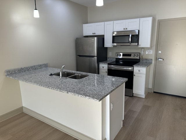 942 Jefferson St, Nashville, TN 37208 - kitchen with stainless steel appliances, light wood-style floors, a peninsula, and white cabinetry
