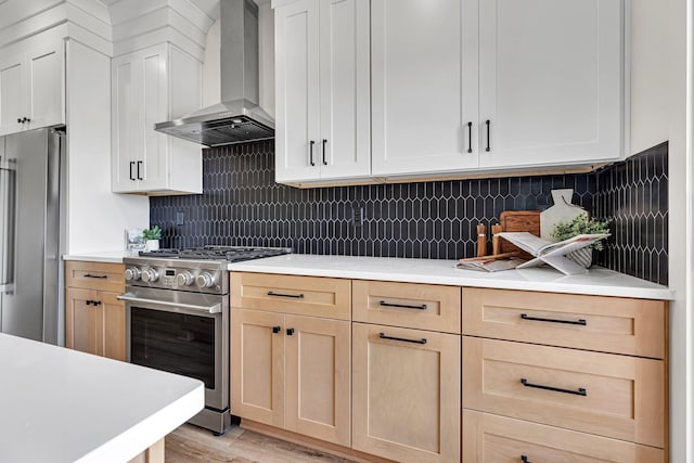 kitchen with decorative backsplash, appliances with stainless steel finishes, light wood-type flooring, light brown cabinetry, and wall chimney exhaust hood