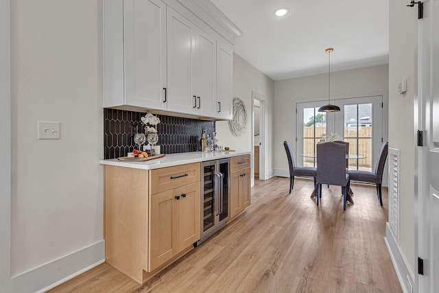 kitchen with decorative backsplash, light hardwood / wood-style floors, decorative light fixtures, and beverage cooler