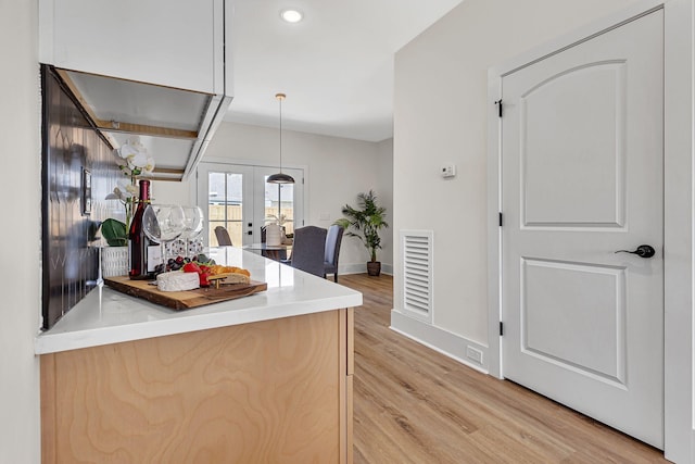 kitchen featuring light brown cabinetry, french doors, pendant lighting, and light wood-type flooring