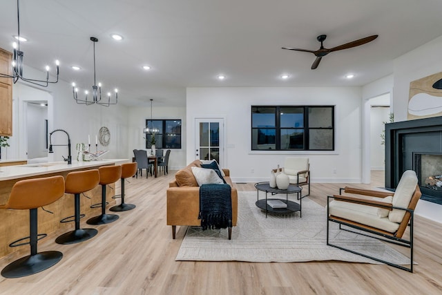 living room featuring ceiling fan, light wood-type flooring, and sink