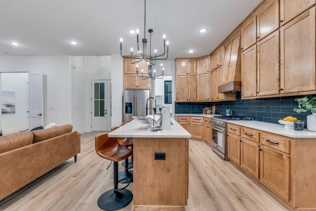 kitchen with stainless steel appliances, tasteful backsplash, light hardwood / wood-style floors, a kitchen bar, and a center island with sink