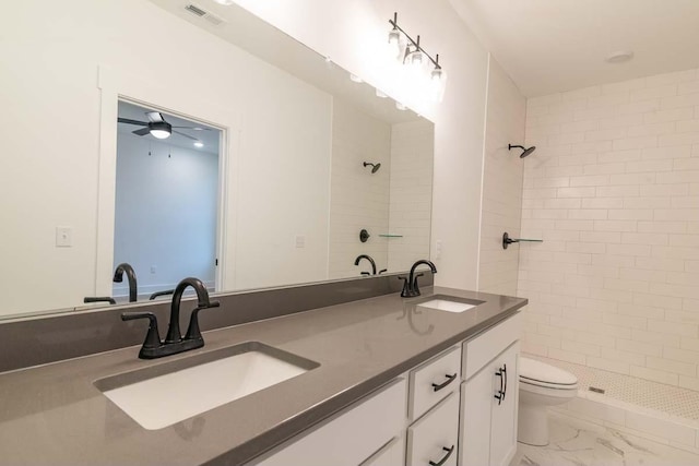 bathroom with vanity, ceiling fan, toilet, and tiled shower