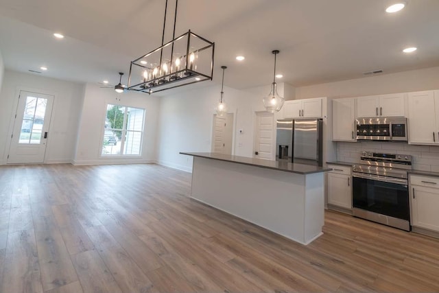 kitchen with white cabinets, appliances with stainless steel finishes, tasteful backsplash, and pendant lighting