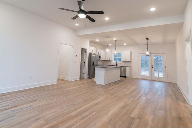 kitchen featuring french doors, stainless steel appliances, a center island, white cabinetry, and hanging light fixtures