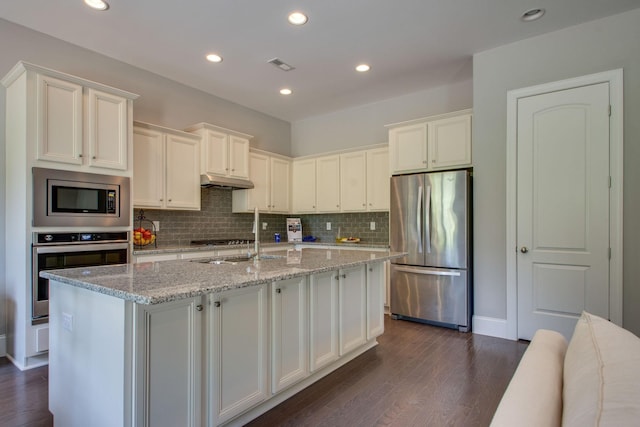 kitchen with a kitchen island with sink, dark wood-type flooring, light stone countertops, white cabinetry, and stainless steel appliances