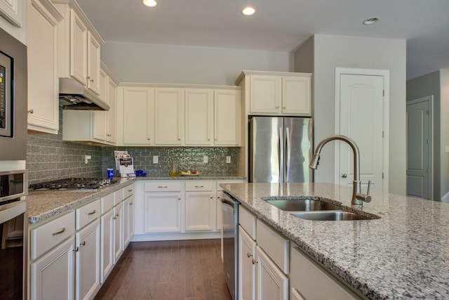 kitchen with backsplash, light stone counters, stainless steel appliances, sink, and dark hardwood / wood-style floors