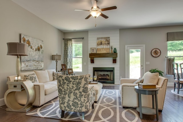 living room with ceiling fan, a large fireplace, and wood-type flooring