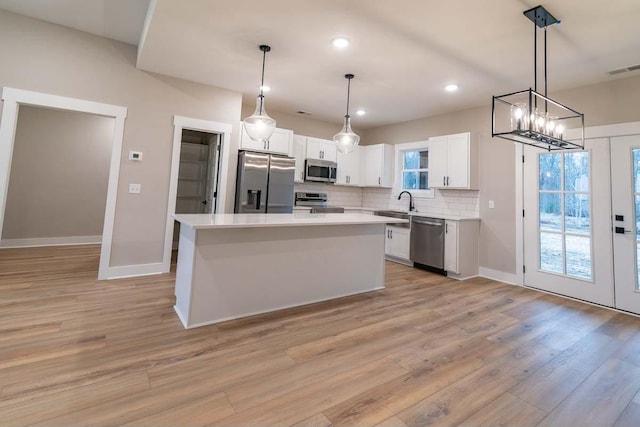 kitchen with a center island, white cabinetry, stainless steel appliances, and hanging light fixtures