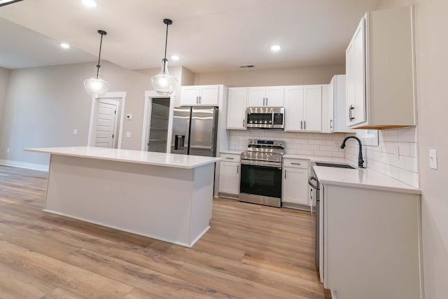 kitchen featuring white cabinets, sink, a kitchen island, and appliances with stainless steel finishes