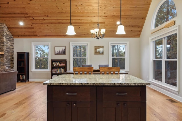 kitchen with pendant lighting, dark brown cabinetry, and vaulted ceiling