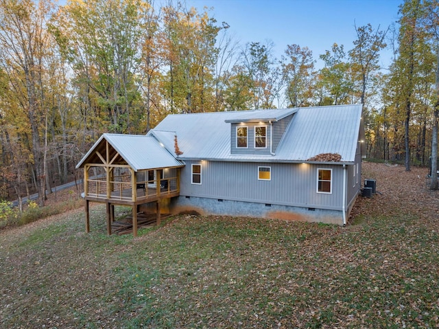 rear view of property with central AC, a wooden deck, and a lawn