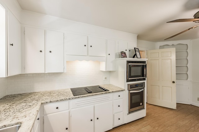 kitchen featuring black appliances, light stone countertops, white cabinetry, and tasteful backsplash