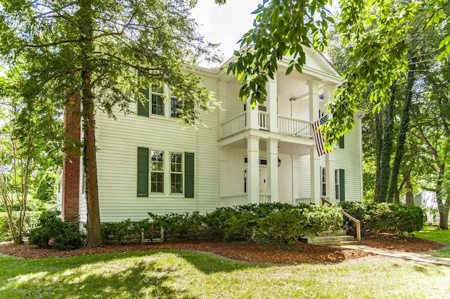 view of front of house featuring a balcony and a front lawn