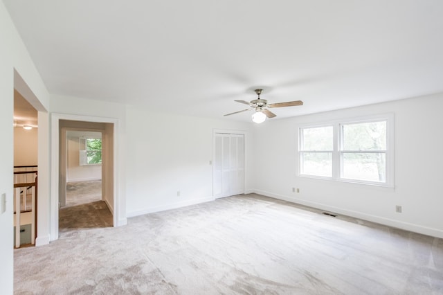 empty room with light colored carpet, a wealth of natural light, and ceiling fan