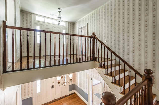 stairway with hardwood / wood-style floors and crown molding