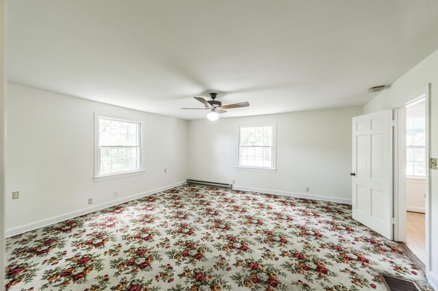 empty room featuring ceiling fan and a baseboard heating unit