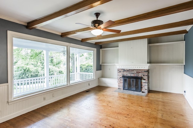 unfurnished living room with a brick fireplace, ceiling fan, beamed ceiling, and light hardwood / wood-style flooring