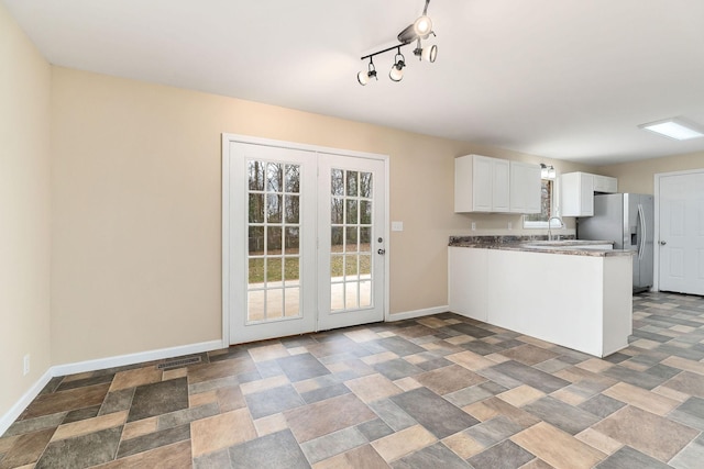 kitchen with white cabinetry, sink, rail lighting, kitchen peninsula, and stainless steel fridge