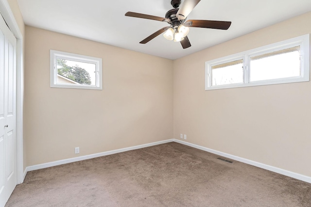 spare room with carpet, a wealth of natural light, and ceiling fan