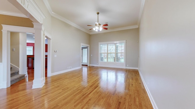 empty room featuring decorative columns, light wood-style flooring, baseboards, and ceiling fan