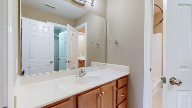 bathroom with a tub to relax in, visible vents, and vanity