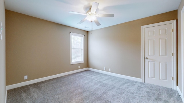 carpeted spare room featuring ceiling fan and baseboards