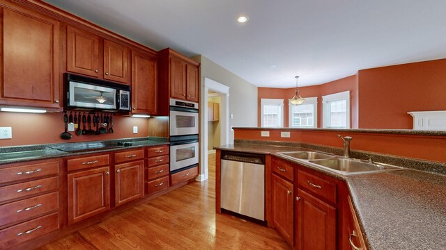 kitchen with dark countertops, pendant lighting, stainless steel appliances, and a sink