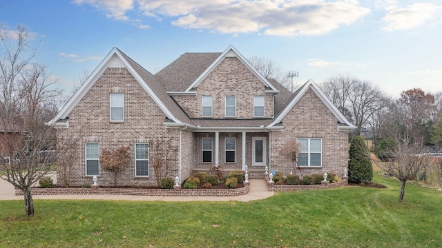 craftsman-style home featuring a shingled roof, a front lawn, and brick siding