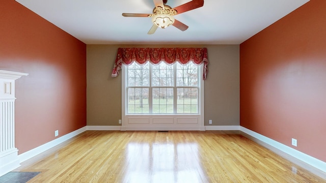 spare room with light wood-type flooring, ceiling fan, and baseboards