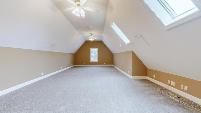 additional living space with light carpet, ceiling fan, lofted ceiling with skylight, and baseboards