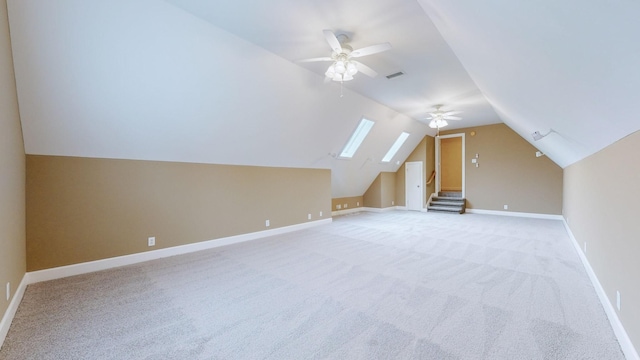 bonus room featuring visible vents, baseboards, light colored carpet, lofted ceiling with skylight, and ceiling fan