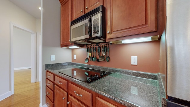 kitchen with appliances with stainless steel finishes, brown cabinetry, light wood-style floors, and baseboards