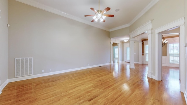 empty room with light wood finished floors, decorative columns, visible vents, and crown molding