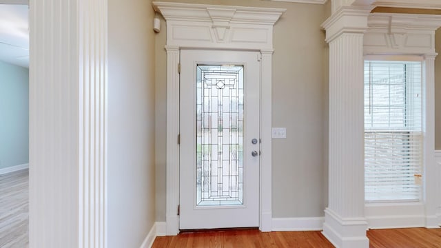 entrance foyer featuring ornate columns, baseboards, and light wood-style floors