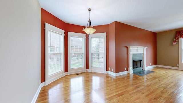 unfurnished living room with light wood-type flooring, visible vents, a fireplace, and baseboards