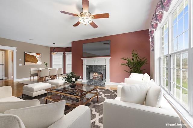 living room featuring a healthy amount of sunlight, baseboards, wood finished floors, and a tile fireplace