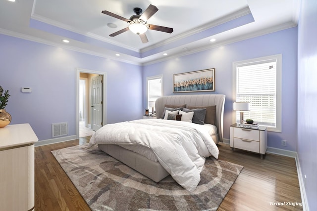 bedroom featuring dark wood-type flooring, a raised ceiling, visible vents, and baseboards