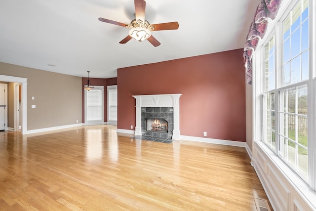 unfurnished living room with light wood-type flooring, visible vents, baseboards, and a premium fireplace