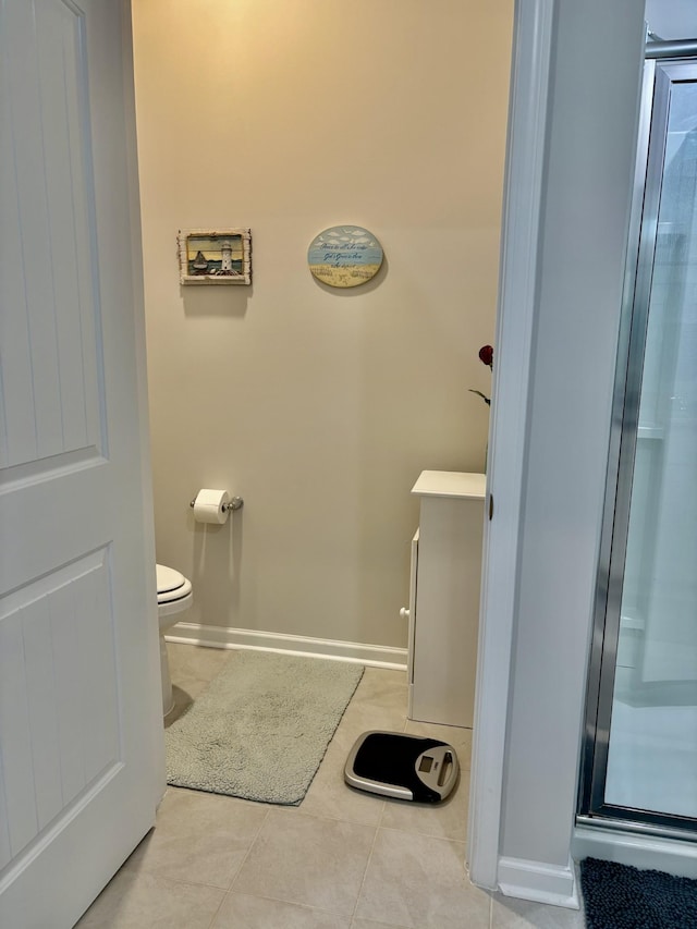 bathroom featuring tile patterned flooring, toilet, and an enclosed shower