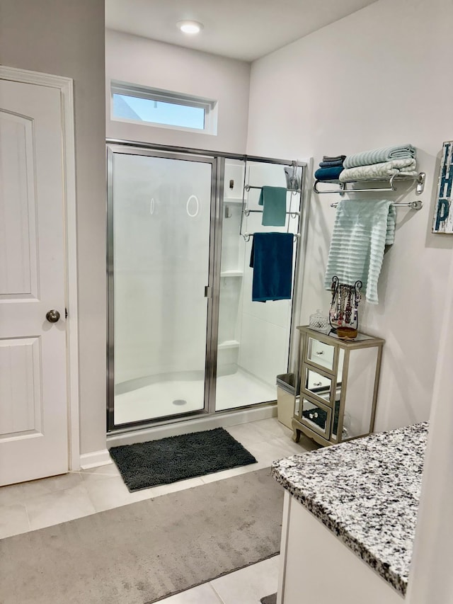 bathroom with tile patterned flooring, vanity, and walk in shower