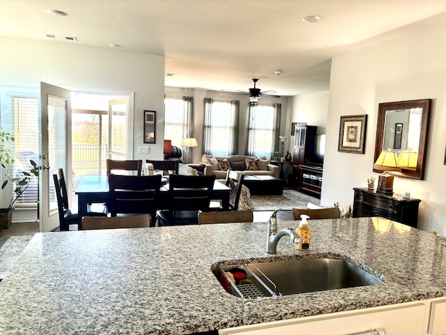 kitchen with ceiling fan, light stone countertops, and sink