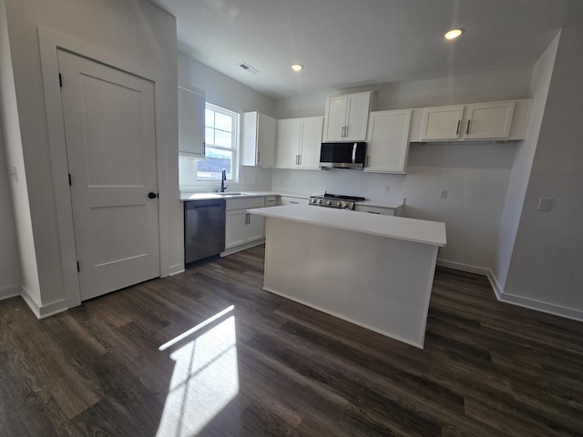 kitchen featuring appliances with stainless steel finishes, a center island, white cabinets, and dark hardwood / wood-style floors