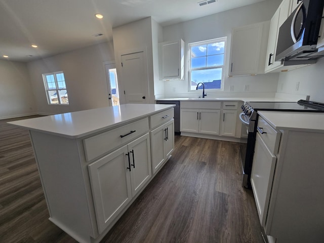 kitchen featuring electric stove, sink, white cabinetry, plenty of natural light, and a kitchen island